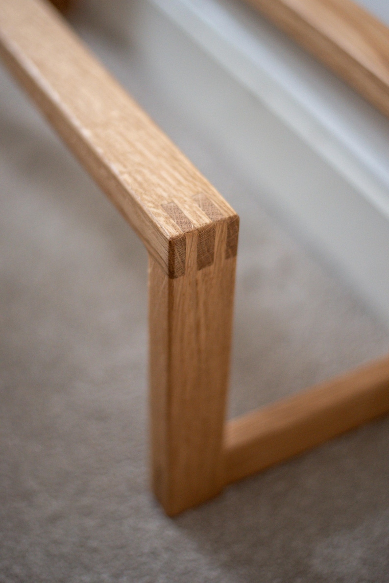 May include: Close-up of a wooden frame with a mitred joint. The wood is light brown and has a natural finish.