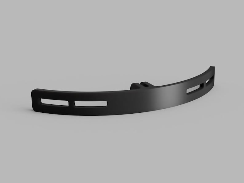 May include: A matte black curved bracket featuring a central mounting point and four elongated horizontal slots. The component has a smooth, solid finish and a semi-circular profile, designed with a uniform thickness throughout its structure.