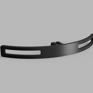 May include: A matte black curved bracket featuring a central mounting point and two elongated horizontal rectangular cutouts on either side. The component has a smooth finish and a symmetrical design with a solid center section and open ends.