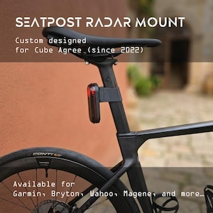 Pode incluir: Um suporte de radar para espigão de selim preto fixado a um espigão de bicicleta, com o texto SEATPOST RADAR MOUNT, Custom designed for Cube Agree (since 2022), e Available for Garmin, Bryton, Wahoo, Magene, and more.