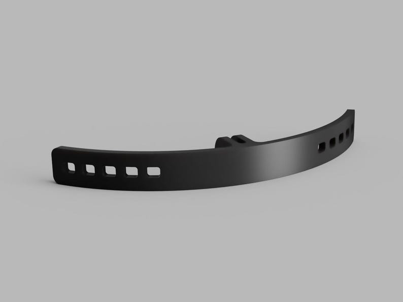 May include: A matte black curved plastic component featuring a series of rectangular cutouts along its length and a central mounting bracket with two small vertical tabs, designed for attachment or structural support in a mechanical assembly.