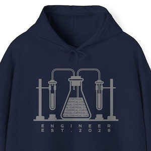 May include: Navy blue hoodie with a gray graphic of laboratory equipment, including beakers and test tubes. The text "ENGINEER EST. 2026" is printed below the graphic. The hoodie has a drawstring hood.