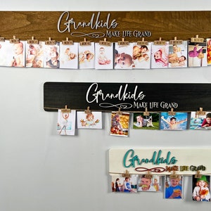 Puede incluir: Tres tableros de exhibición de fotos de madera con el texto "Grandkids Make Life Grand" en cada uno. Los tableros tienen un acabado de madera rústica, negro y blanco. Cada tablero tiene una cuerda con pinzas para sujetar fotos.