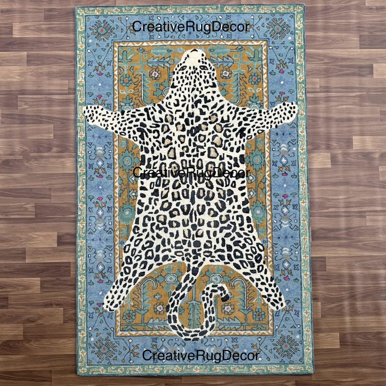 May include: A rectangular rug with a leopard print design in the center, surrounded by a blue and gold border. The leopard print features black spots on a white background. The rug has the text "CreativeRugDecor" in the corners.