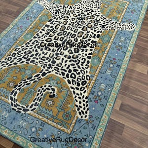 May include: A rectangular rug with a leopard print design in the center, surrounded by a blue and gold border. The rug has a distressed, vintage look. The text "CreativeRugDecor" is visible on the rug.