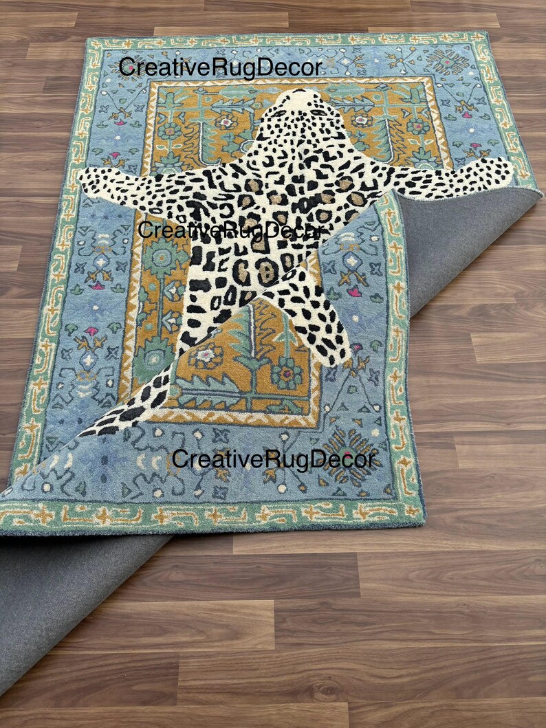 May include: A rectangular rug with a light blue border and a central design featuring a leopard pattern. The leopard design is in black and white spots. The rug has the text "CreativeRugDecor" in multiple places.