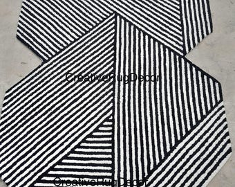 May include: Black and white striped geometric area rug with a hexagonal shape. The rug has a modern design with a repeating pattern of stripes.