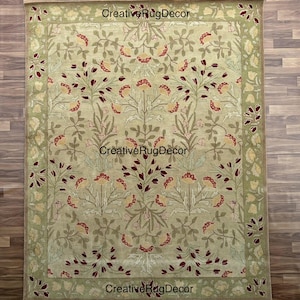 May include: A green and beige area rug with a floral pattern. The rug has a border with a repeating pattern of green, beige, and red.