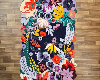 May include: A rectangular floral rug with a dark blue background and a variety of colorful flowers in shades of red, orange, yellow, purple, and green. The rug has a scalloped edge and is placed on a wooden floor.