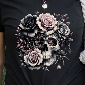 May include: Black t-shirt with a graphic of a skull surrounded by pink and black roses, a spider, and a web.