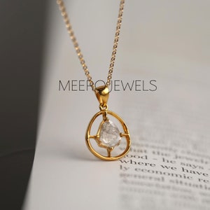 May include: A gold chain necklace with a pendant featuring a clear, faceted gemstone set in a gold frame. The pendant is in the shape of a teardrop.