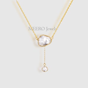 May include: A gold chain necklace with two large, clear, rough-cut diamonds. The diamonds are set in gold and hang from the chain. The necklace is a Y-shape, with the diamonds hanging from the bottom of the Y.