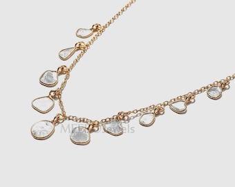 Puede incluir: Un collar de cadena de oro con múltiples piedras pequeñas, transparentes e irregulares que cuelgan de él. Las piedras están engastadas en oro.