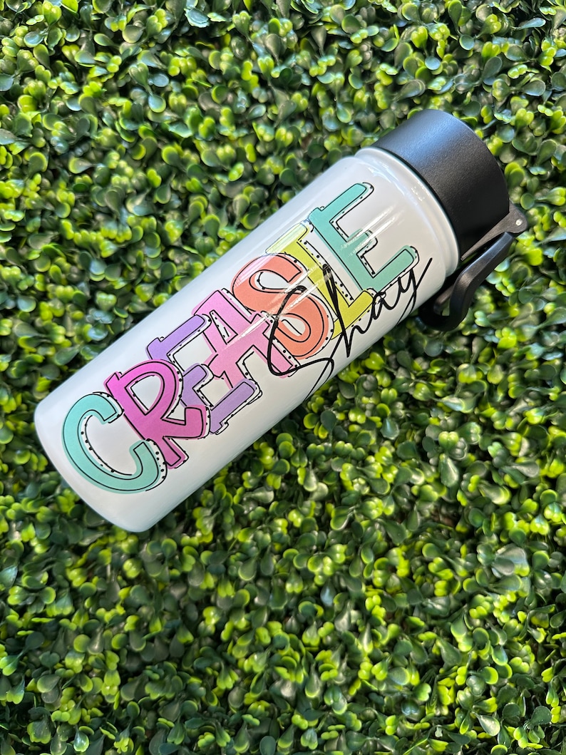 May include: White water bottle with a black lid and a colorful graphic that says "Create & Love" with a signature underneath.