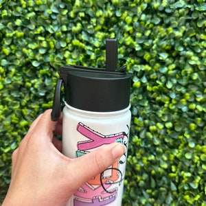 May include: White reusable water bottle with a black lid and a straw. The bottle has a colorful design with the word "Kelly" written in a playful font.