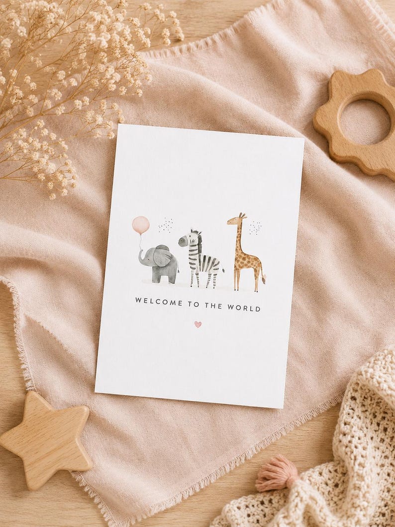 May include: A white rectangular greeting card featuring a watercolor illustration of a gray elephant holding a pink balloon, a black and white zebra, and a brown giraffe. The text WELCOME TO THE WORLD is printed in black below the animals.