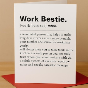 Könnte beinhalten: Eine weiße Grußkarte mit dem Text "Work Bestie" in fetter schwarzer Schrift. Die Karte definiert "Work Bestie" als Substantiv und beschreibt eine wunderbare Person, die die Arbeit erträglicher macht und eine Quelle für Büroklatsch ist.