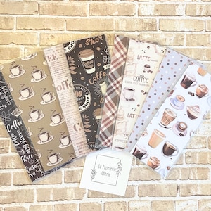 Op de afbeelding: Zes verschillende koffie-thema boekmarkeerontwerpen. De bladwijzers bevatten verschillende koffiegerelateerde illustraties, waaronder koffiekopjes, koffiebonen en tekst. De bladwijzers zijn gedrukt op verschillende papiersoorten, waaronder bruin papier, wit papier en gepatroneerd papier. De bladwijzers bevinden zich allemaal in een doorzichtige plastic hoes.
