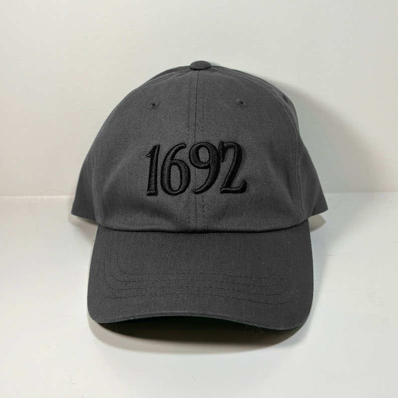May include: A dark gray baseball cap with the number "1692" embroidered in black on the front.