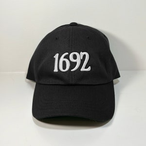 May include: A black baseball cap with a white embroidered number "1692" on the front.
