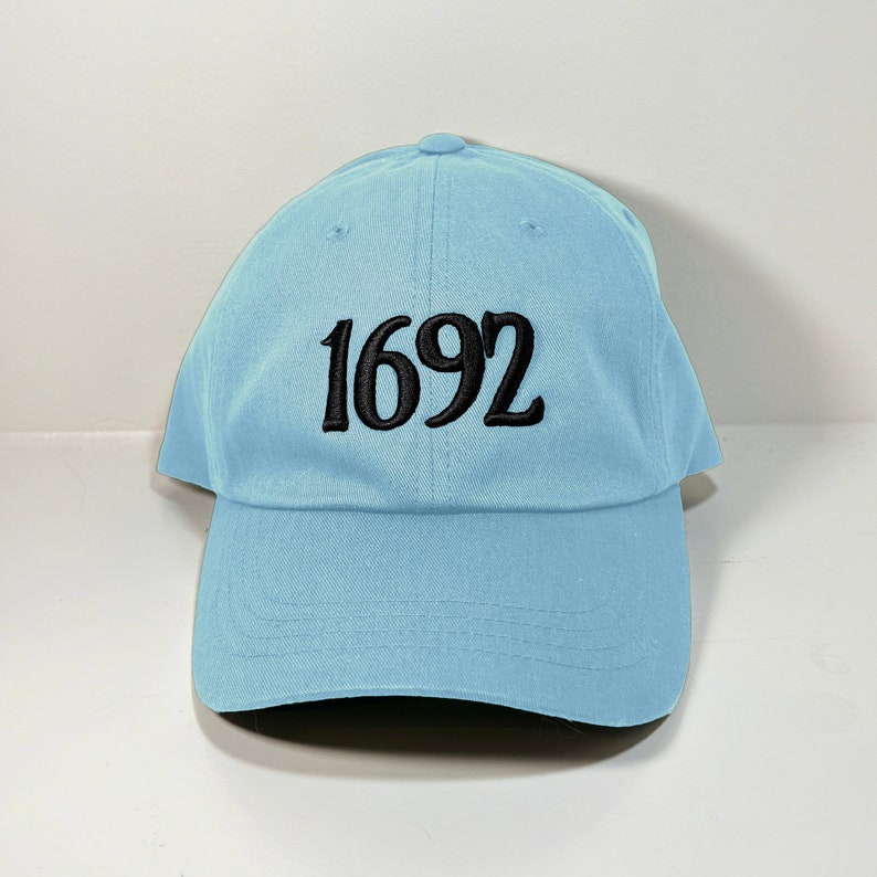 May include: A light blue baseball cap with black embroidery of the number "1692".