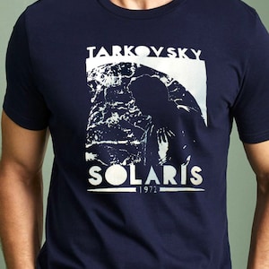 Könnte beinhalten: Ein marineblaues T-Shirt mit einem weißen Grafikdruck eines Planeten und dem Text "Tarkovsky Solaris 1972".