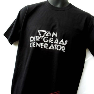 Op de afbeelding: Zwart T-shirt met witte tekst die "Van Der Graaf Generator" luidt in een gestileerd lettertype. De tekst is in de vorm van een driehoek gerangschikt. Een rode stempel met het woord "Goodluff" bevindt zich in de rechterbenedenhoek.