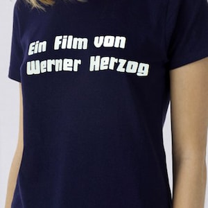 May include: A navy blue t-shirt with white text that reads "Ein Film von Werner Herzog".
