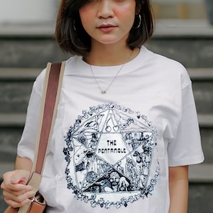 May include: White t-shirt with a black and white graphic of a pentagram with the text "The Pentangle" inside. The graphic is surrounded by a wreath of flowers.