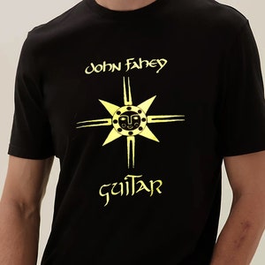 Op de afbeelding: Zwart T-shirt met een geel grafisch ontwerp met een gestileerde zon met een gezicht en de tekst "john fahey guitar"