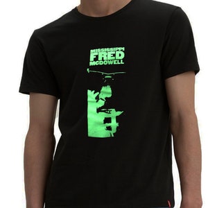 May include: Black t-shirt with a green graphic print of a person's face and the text "MISSISSIPPI FRED MCDOWELL".