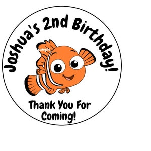 May include: A round sticker with a cartoon orange and white clownfish with big eyes. The text "Joshua's 2nd Birthday!" is written in a black circle around the fish. Below the fish is the text "Thank You For Coming!"