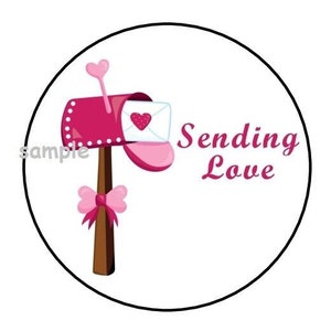 May include: A pink mailbox with a white envelope and a heart design. The mailbox has a brown post and a pink bow. The text "Sending Love" is written in pink letters.