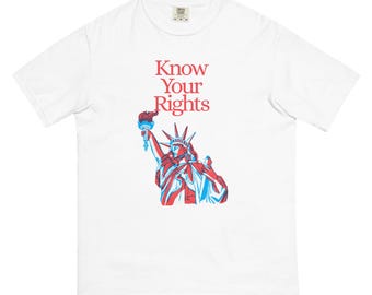 May include: White t-shirt featuring the text "Know Your Rights" in red, above a red and blue graphic of the Statue of Liberty holding a torch. The shirt is made of a soft, comfortable material.