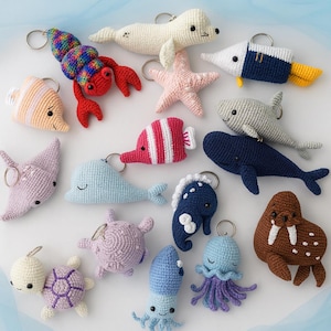 Può includere: Una collezione di portachiavi all'uncinetto a forma di creature marine, tra cui un'aragosta, una foca, una stella marina, un pesce, uno squalo, una balena, un cavalluccio marino, una tartaruga, un polpo e un tricheco. Ogni portachiavi è di un colore diverso e ha un anello di metallo.