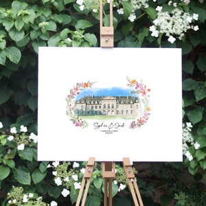 May include: A watercolor painting of a stately building, framed by a floral wreath, displayed on a wooden easel. The artwork features the names "Sophie & Jack" and a date. The background is a lush green wall of foliage.