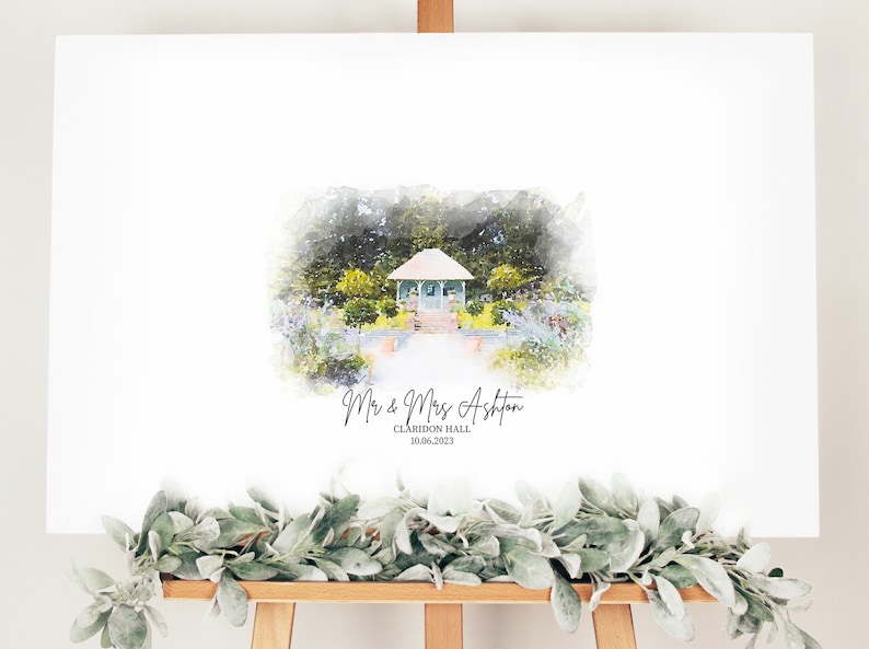 May include: A white wedding sign on an easel featuring a watercolor painting of a gazebo in a garden. The sign includes the names "Mr & Mrs Ashton", the venue "Claridon Hall", and the date "10.06.2023". A garland of green leaves adorns the bottom.