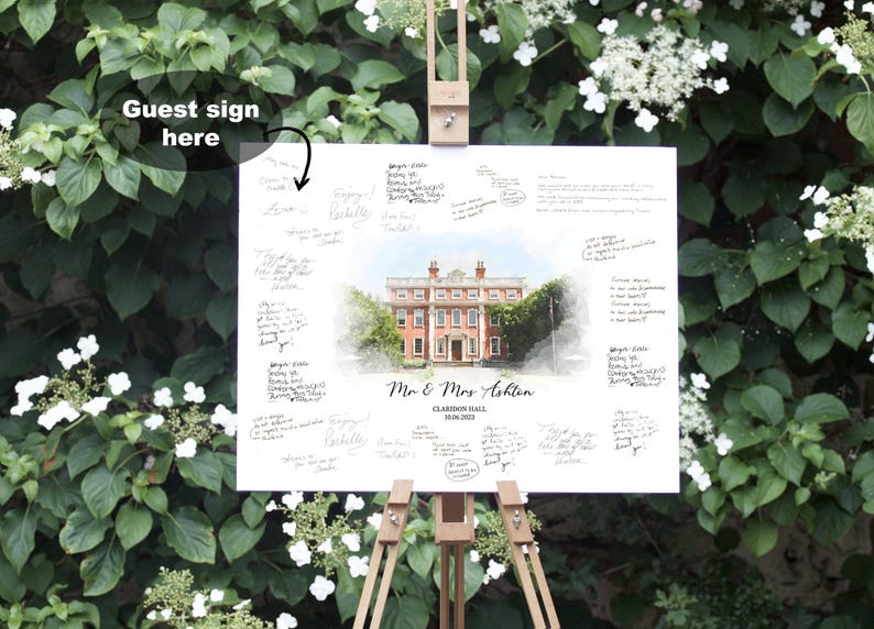 May include: A white guest sign on a wooden easel, surrounded by greenery. The sign features a watercolor painting of a stately building and the names "Mr & Mrs Ashton" with the date "10.06.2023". Handwritten messages surround the painting.