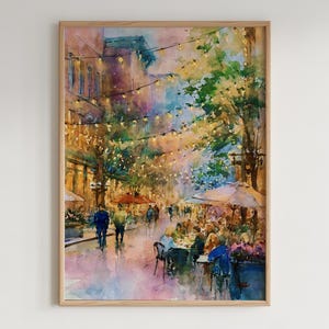 May include: Watercolour painting of a European street scene with people dining at outdoor cafes. The artwork features warm colours, string lights, and a wooden frame. The style is impressionistic, capturing the ambiance of a bustling city.