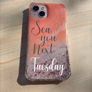 May include: Clear phone case with a coral and white marbled design. The case features the text "Sea you Next Tuesday" in a script font. The bottom of the case is filled with clear beads and small pink beads.
