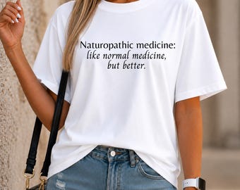 May include: White t-shirt with the text "Naturopathic medicine: like normal medicine, but better." The shirt is paired with blue denim jeans. A black purse and a white watch are also visible.