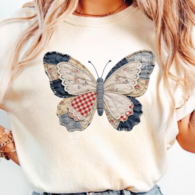 Pu&ograve; includere: Una maglietta color crema con un grande disegno a farfalla patchwork. La farfalla ha ali in denim blu, a motivi floreali e a quadri rossi e bianchi, con un bordo in pizzo bianco. Il testo "DO NOT COPY" &egrave; visibile.