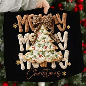 May include: Black Christmas-themed tote bag with embroidered text and design. The design features a Christmas tree with a leopard print bow, red berries, and the words "Merry Christmas" in a decorative font. Gold snowflakes accent the design.