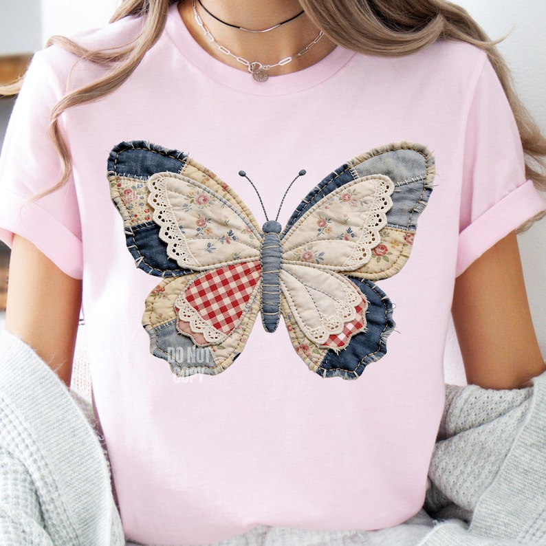 Pu&ograve; includere: T-shirt rosa chiaro con un grande disegno a farfalla. La farfalla &egrave; realizzata con patchwork di denim, motivi floreali e tessuti a quadretti. La farfalla ha un bordo in pizzo e un corpo grigio. Il testo "DO NOT COPY" &egrave; visibile.