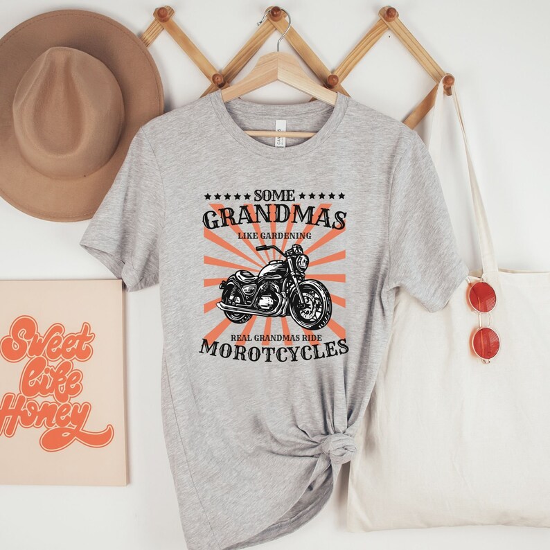 May include: Gray t-shirt with a black and white illustration of a motorcycle. The text on the shirt reads "Some Grandmas Like Gardening Real Grandmas Ride Motorcycles".