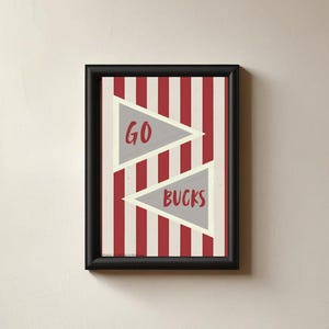 Puede incluir: Impresión artística enmarcada con borde negro. La obra presenta un fondo a rayas rojas y blancas con dos banderines grises. El banderín superior dice "GO" en rojo, y el banderín inferior dice "BUCKS" en rojo.