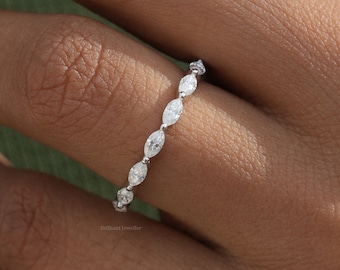 May include: A delicate silver ring with a row of small, oval-shaped diamonds set in a pave setting.