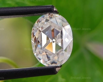May include: A clear, round, faceted gemstone held by tweezers against a green leafy background.