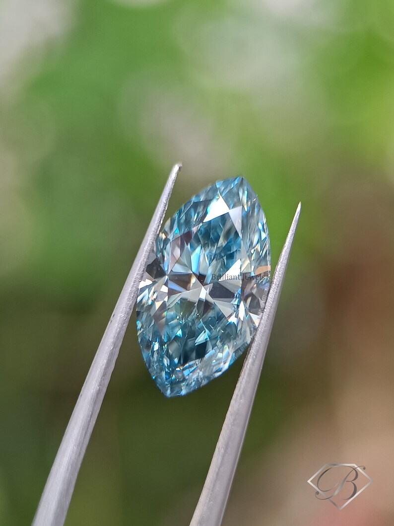 May include: A light blue, faceted, oval-shaped diamond held in tweezers against a green background.