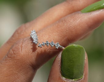 Puede incluir: Un anillo de plata con un diseño en forma de V adornado con pequeñas piedras de circonita cúbica transparentes.